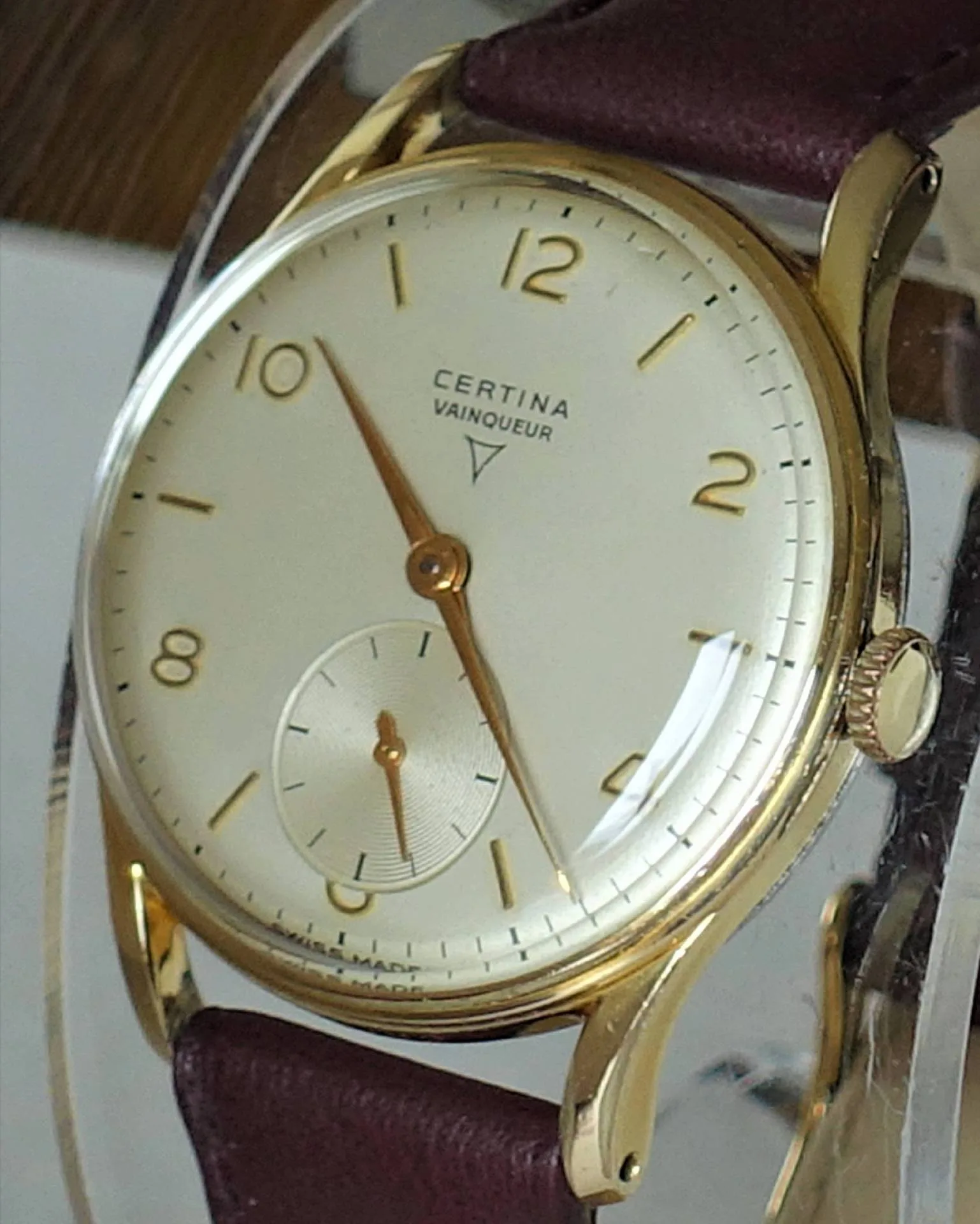 Certina Vainqueur Uhr Klassische Armbanduhr mit hellem Zifferblatt, goldfarbenem Gehäuse und braunem Armband.