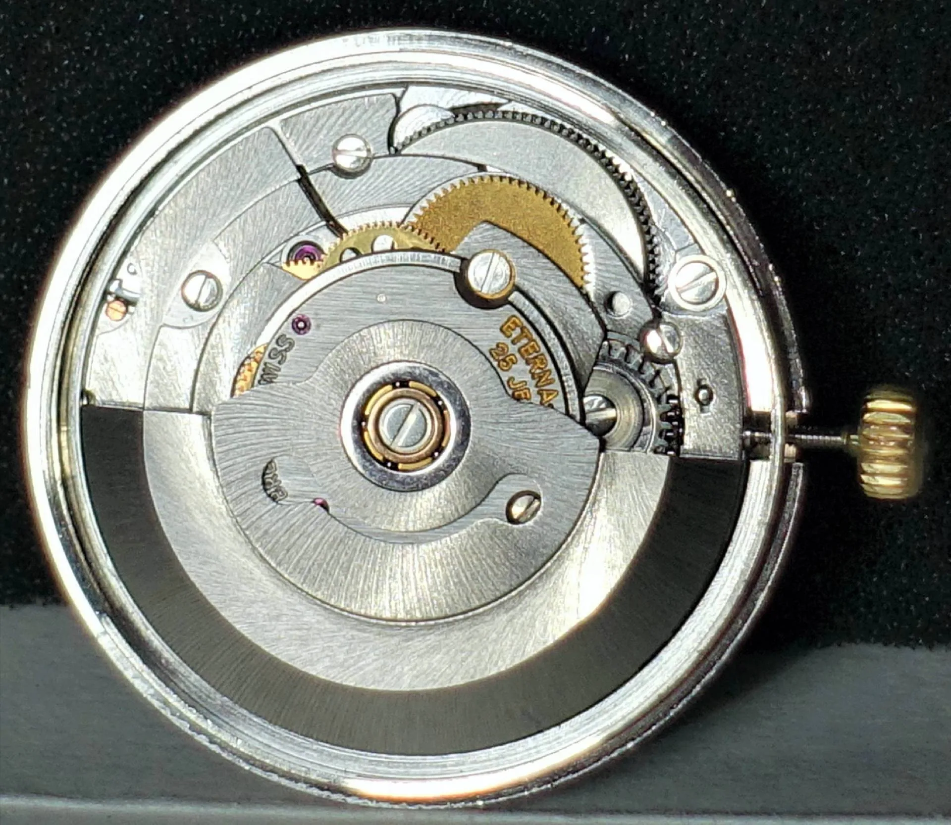 Silberfarbenes Automatik-Uhrwerk mit sichtbaren Zahnrädern und goldfarbener Krone.