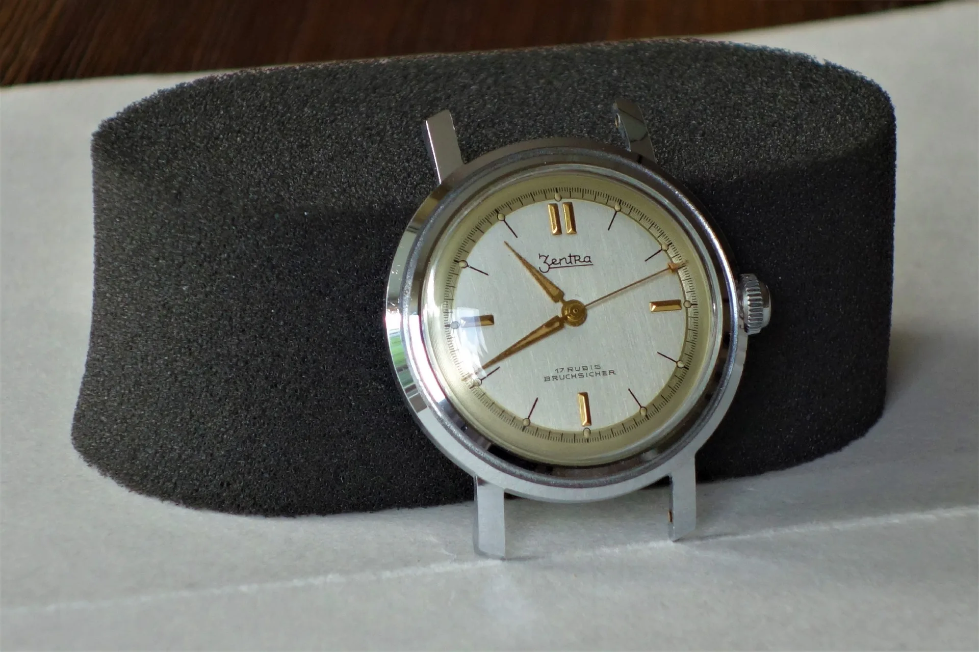 Silberfarbene mechanische Armbanduhr mit hellem Zifferblatt und goldfarbenen Zeigern und Indizes.