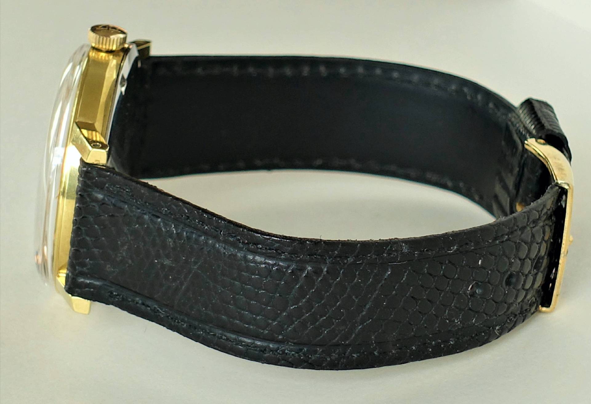 Schwarze Armbanduhr mit goldfarbenem Gehäuse und schwarzem Armband.