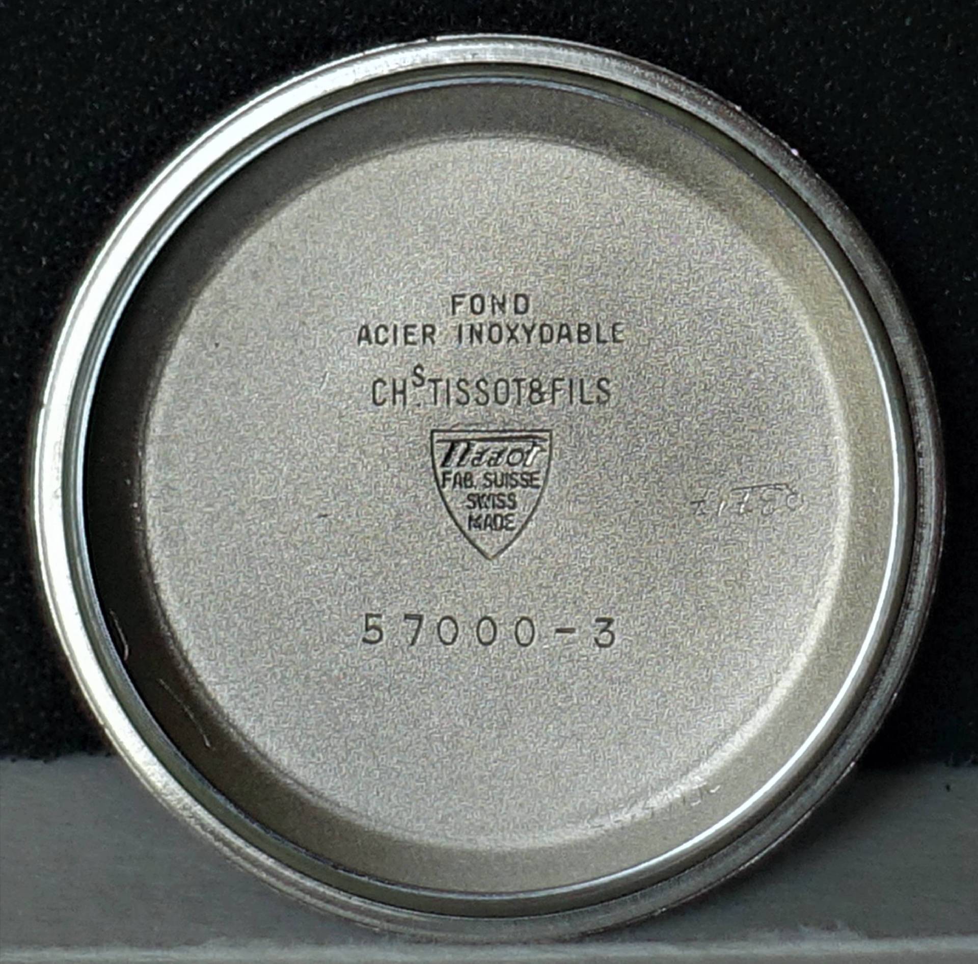 Silberfarbener Gehäuseboden aus Metall mit Tissot-Prägung und Modellnummer.