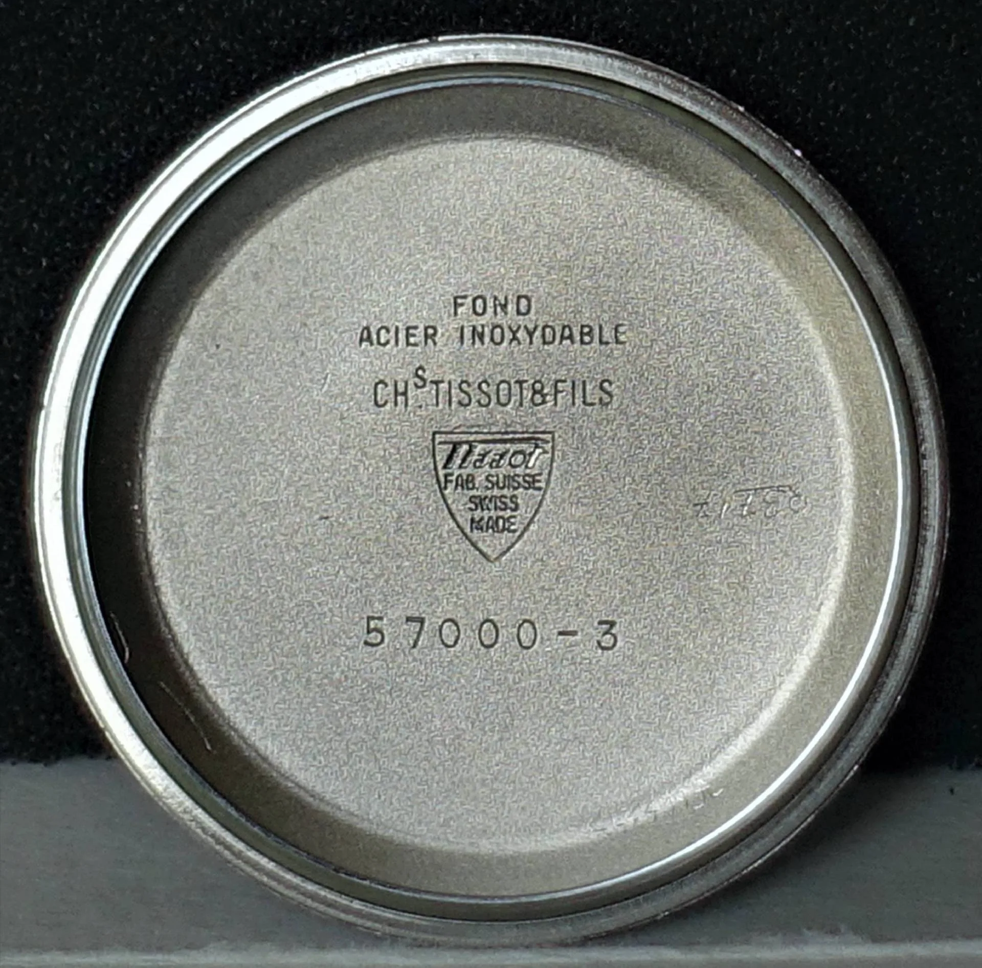 Silberfarbener Gehäuseboden aus Metall mit Tissot-Prägung und Modellnummer.