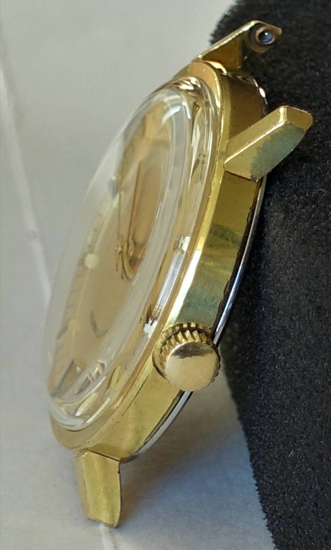 Goldfarbenes Uhrgehäuse mit Krone und Glas, ohne Armband.