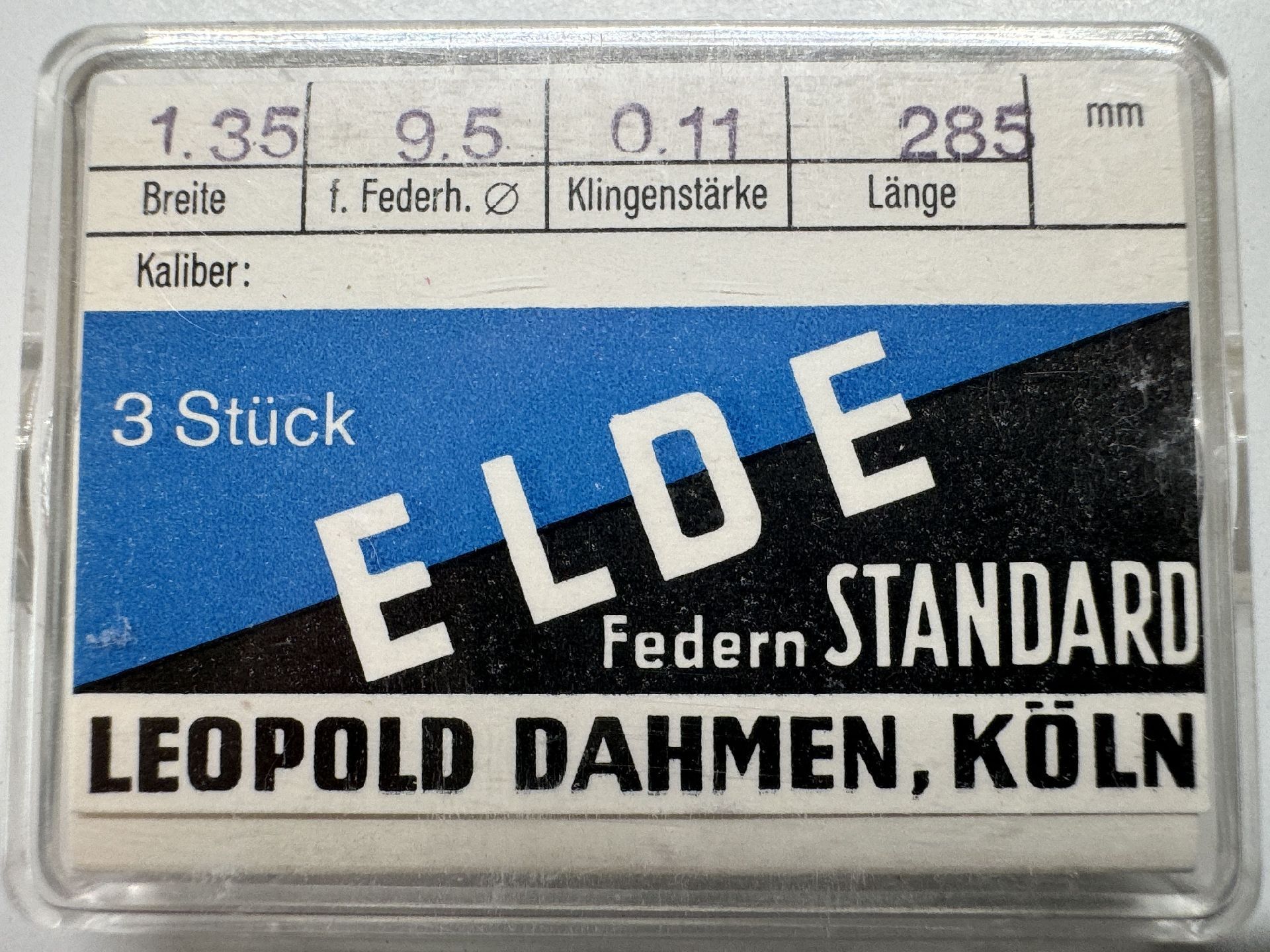 Verpackung mit drei silberfarbenen Aufzugsfedern für Uhrwerke.
