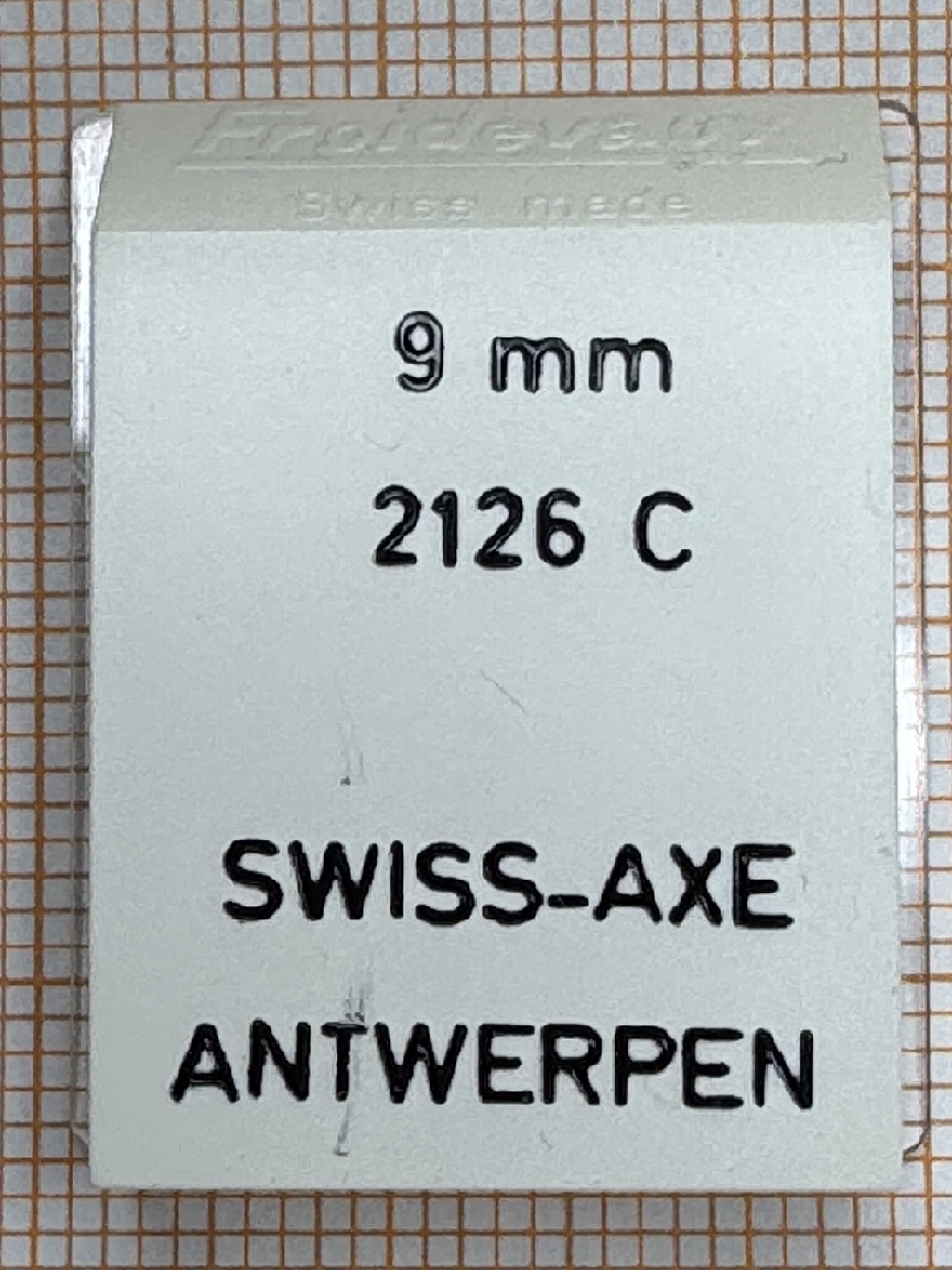 Verpackung für ein 9 Millimeter Uhrwerk Ersatzteil mit der Aufschrift SWISS-AXE ANTWERPEN.