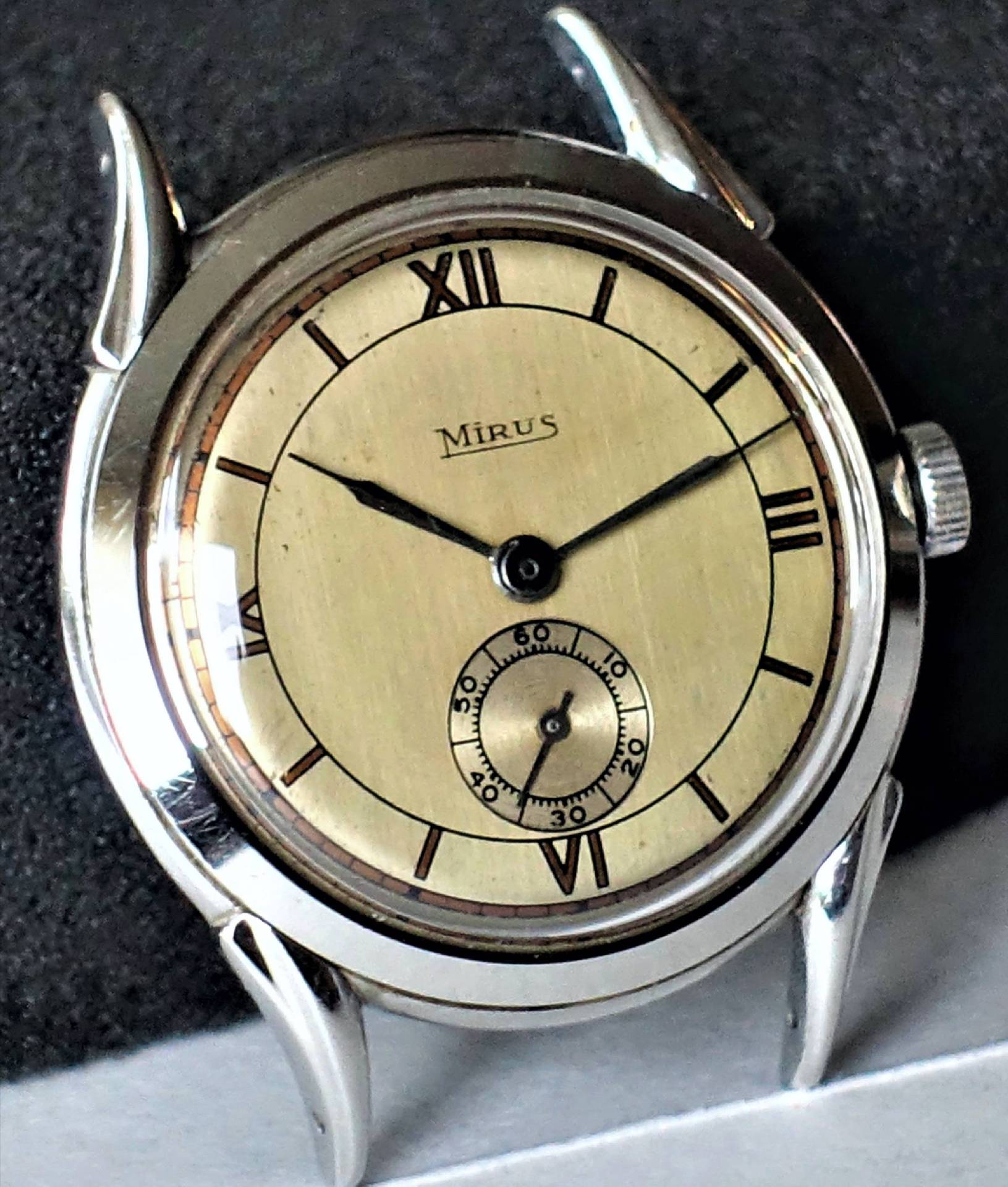 Eine Armbanduhr mit beigem Zifferblatt, schwarzen Zeigern und einem silberfarbenen Gehäuse.