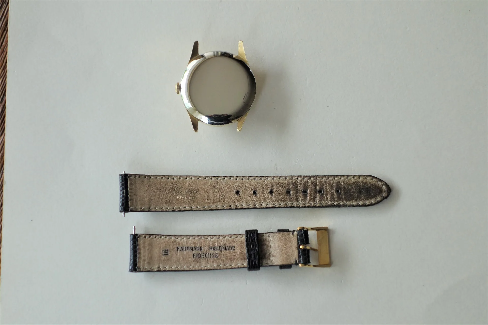 Uhrgehäuse goldfarben und Lederarmband Zerlegtes Uhrgehäuse in goldfarbener Optik mit schwarzem Lederarmband und goldfarbener Schließe.
