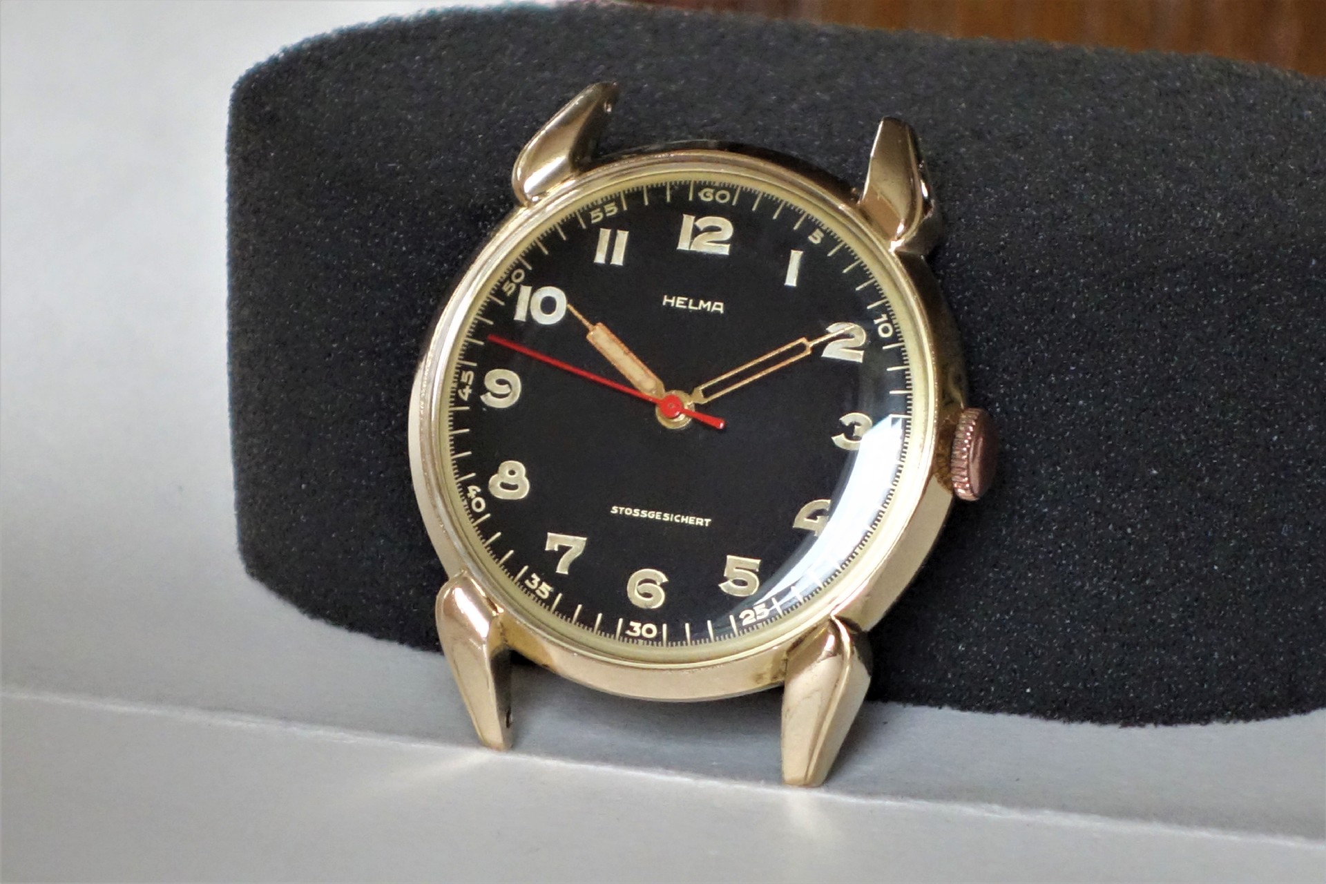 Schwarze Armbanduhr mit goldfarbenem Gehäuse und goldfarbenen Ziffern.