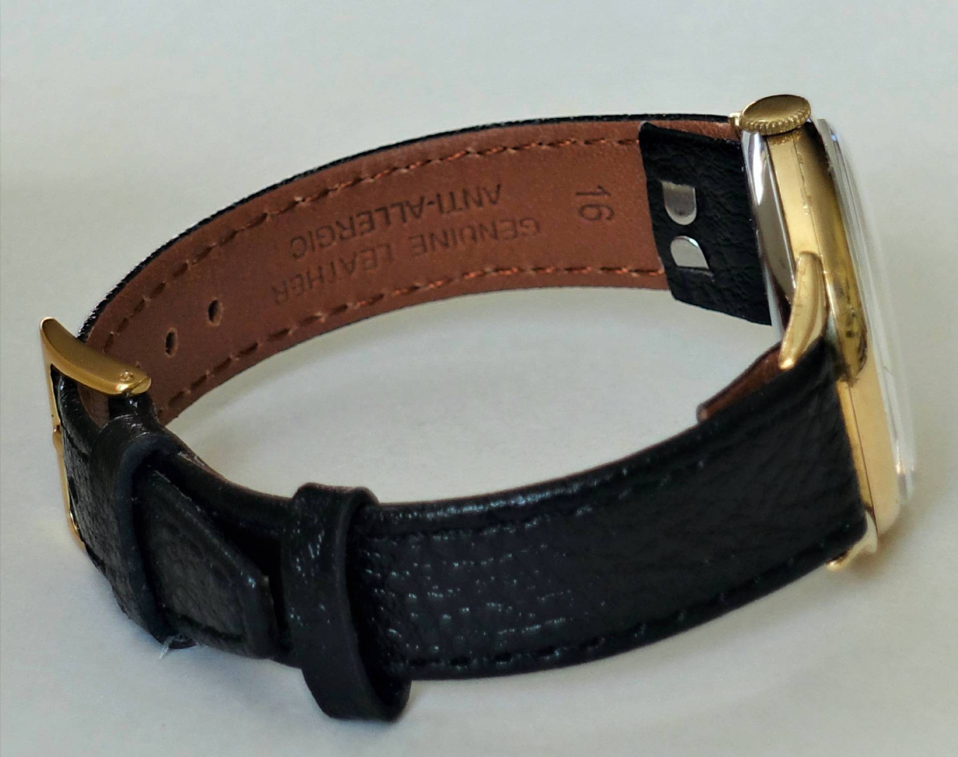 Armbanduhr mit goldfarbenem Gehäuse und schwarzem Lederarmband.