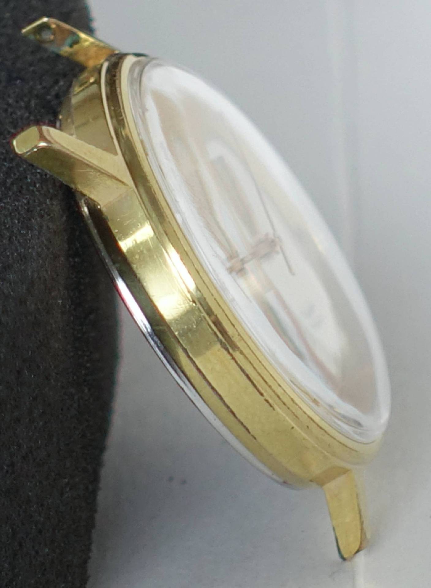 Rundes Uhrengehäuse in goldfarbener Optik mit montiertem Uhrglas.