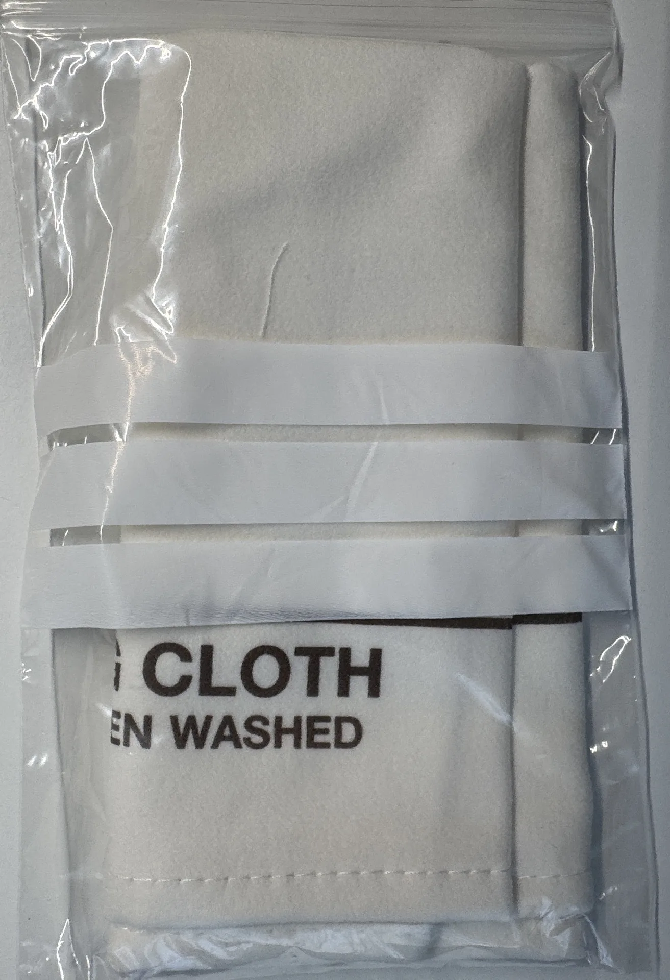 Weißes Reinigungstuch aus Stoff für Uhren, in transparenter Verpackung.