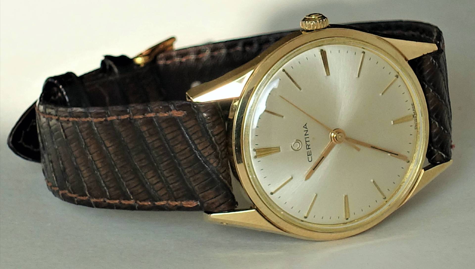 Goldfarbene Certina Armbanduhr mit hellem Zifferblatt und braunem Armband.