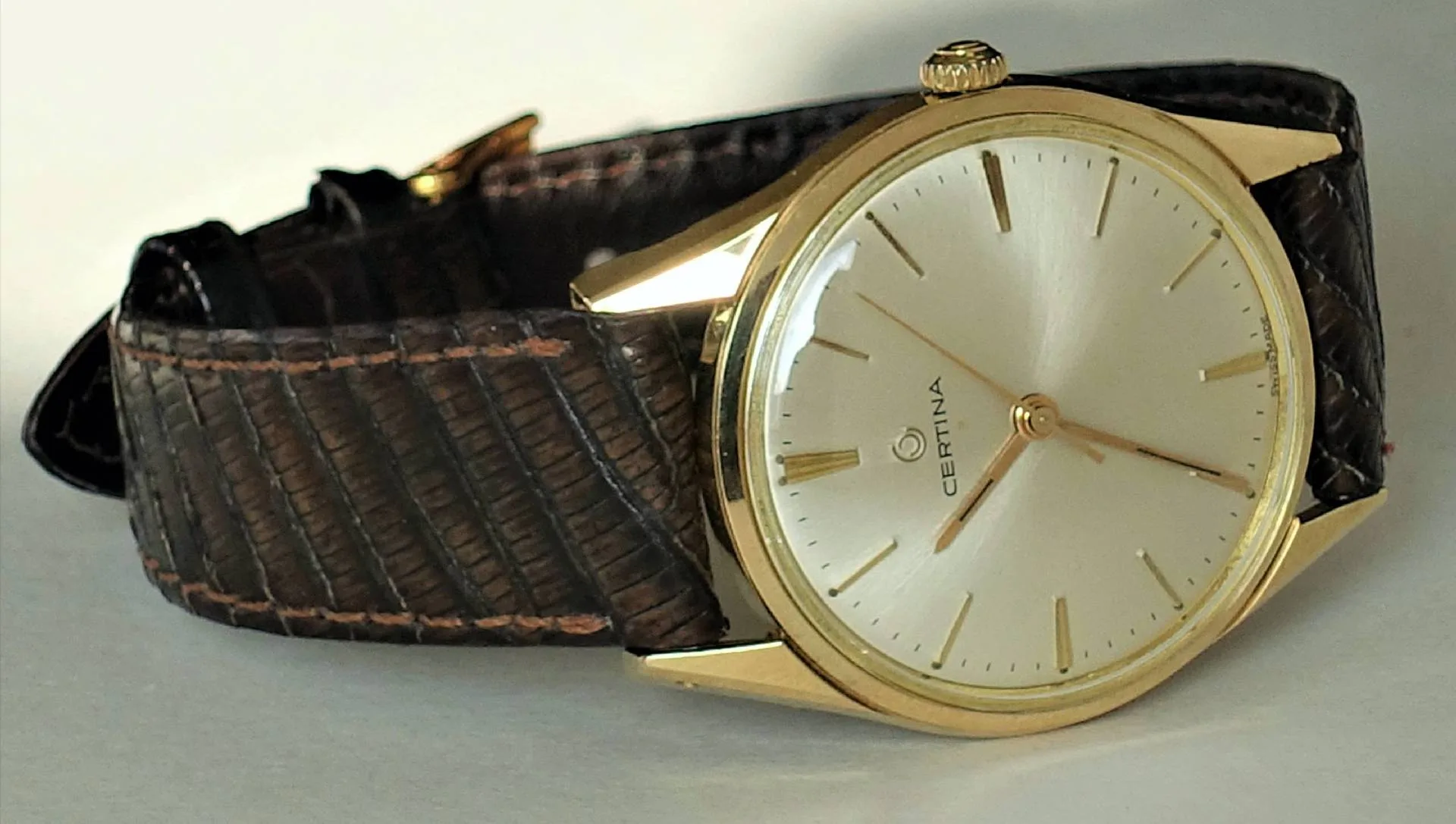 Goldfarbene Certina Armbanduhr mit hellem Zifferblatt und braunem Armband.