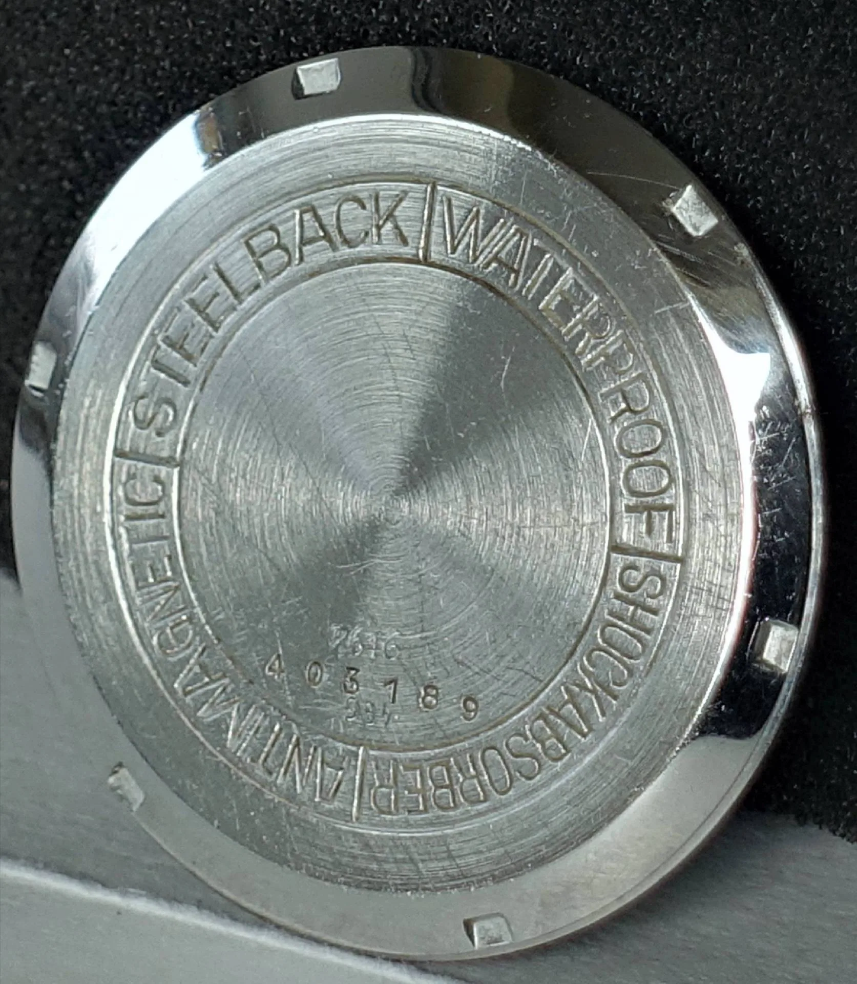 Silberfarbener Gehäuseboden für Armbanduhren mit Gravur.