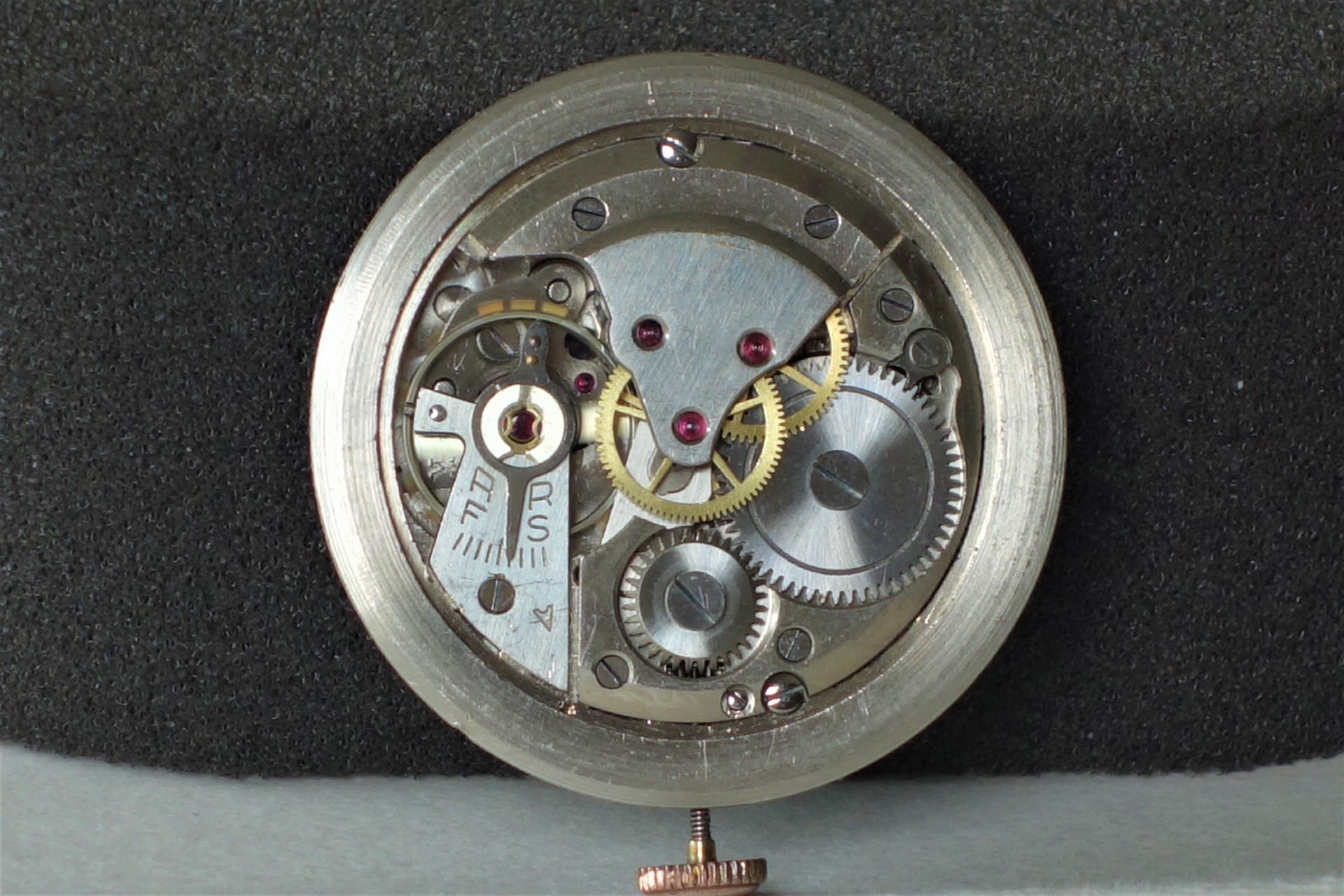 Mechanisches silberfarbenes Uhrwerk mit sichtbaren Zahnrädern und Schrauben.