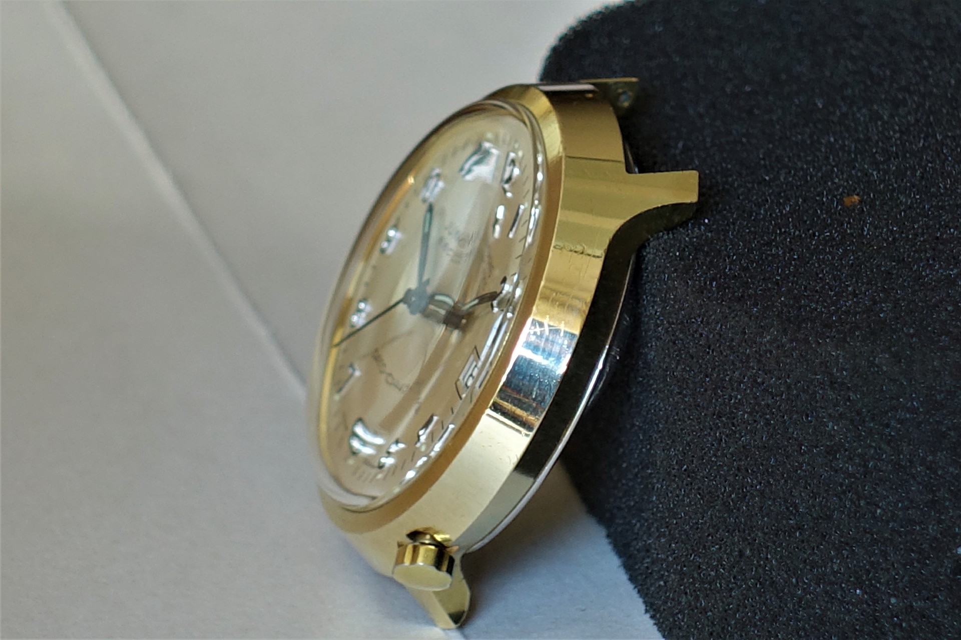 Goldfarbenes Uhrgehäuse mit hellem Zifferblatt und aufgesetzten Indizes.