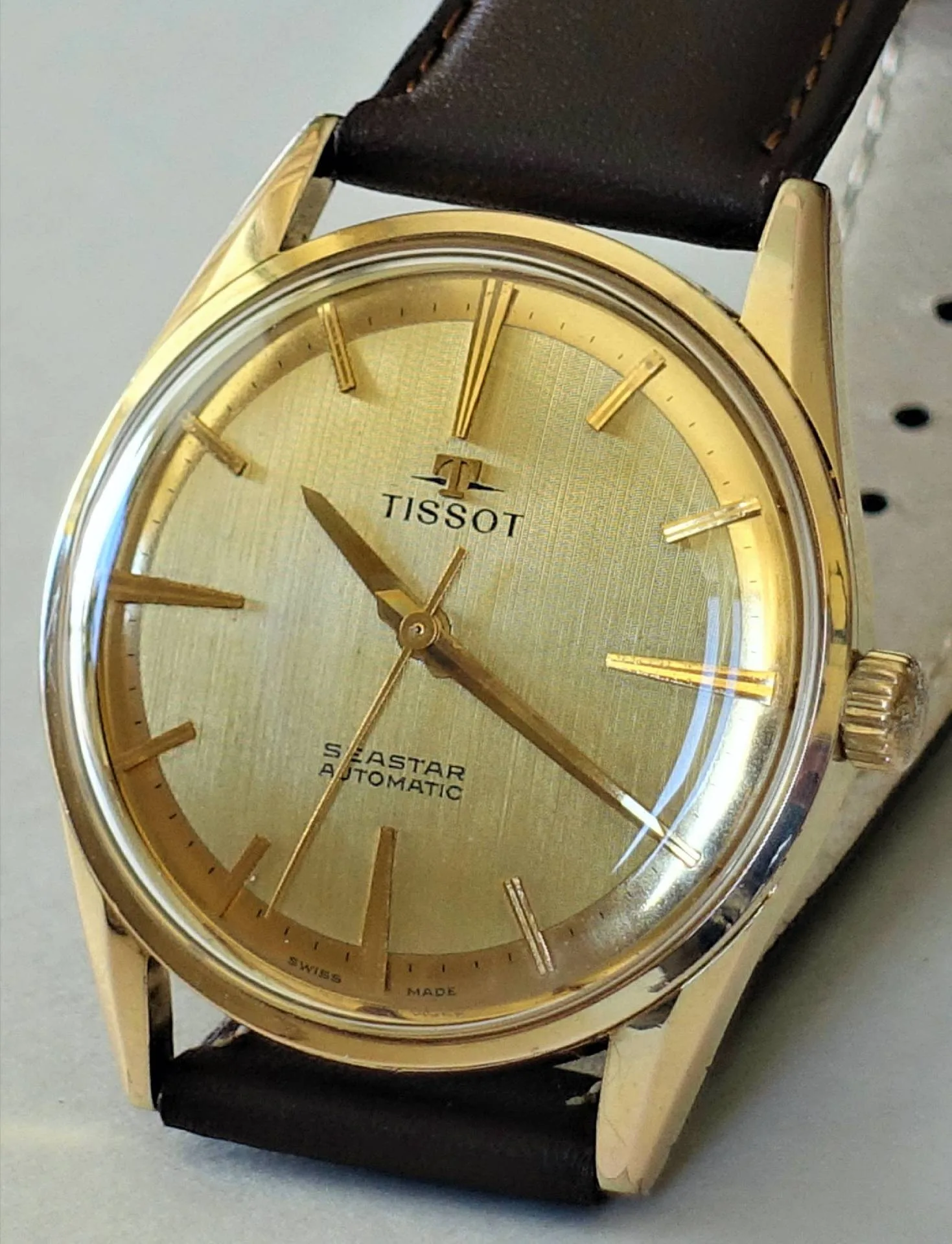 Tissot Seastar Automatikuhr Goldfarbene Armbanduhr mit hellem Zifferblatt und braunem Armband.