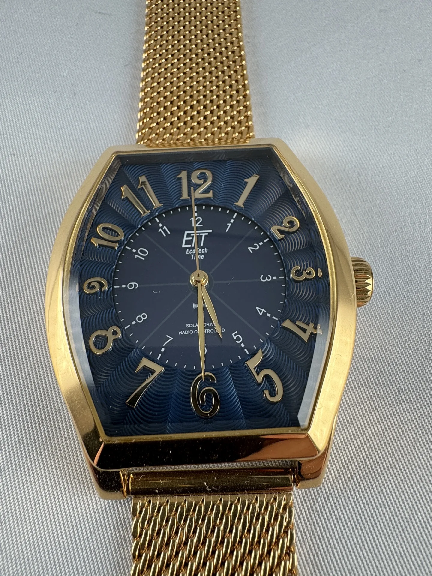 Goldene Funkuhr mit Milanaiseband Goldfarbene Armbanduhr mit blauem Zifferblatt, goldenen Zahlen und Milanaise-Edelstahlarmband.